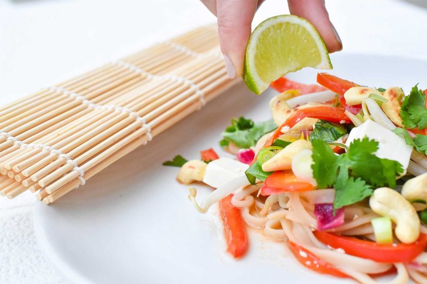 Plant-based tofu vegetable pad thai on white plate with lime wedge