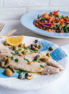 Mediterranean Lentils with Sea Bass on blue & white plates topped with parsley and olives