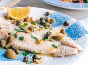 Mediterranean lentils with Sea Bass on blue and white plate served with capers olives and lemon