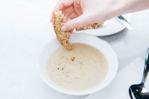 Jerusalem artichoke Soup in white bowl with gluten free bread