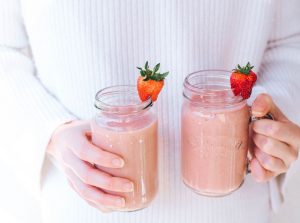 Strawberry and banana smoothie held in girl's hands