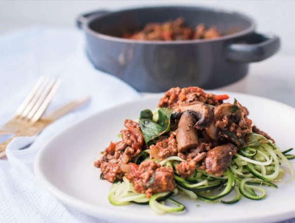 Spiralized Courgetti Bolognese with mushrooms, onion, chilli and basil on white plate